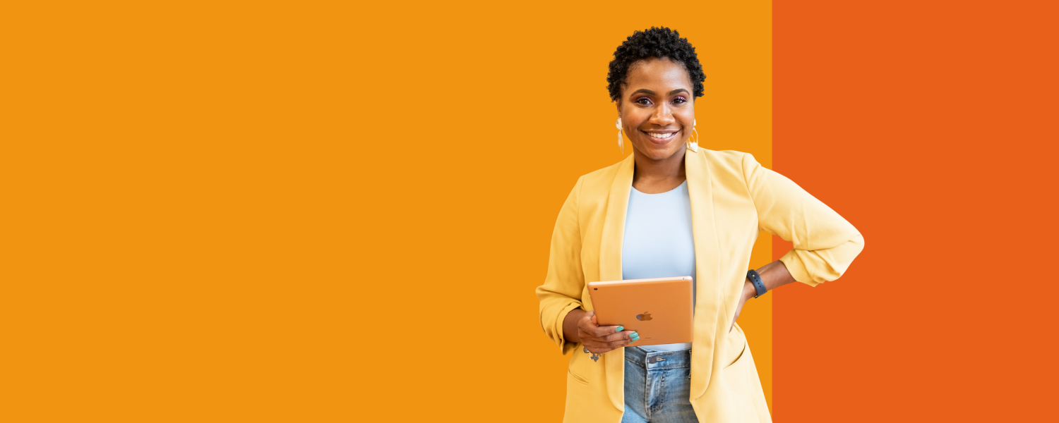 A woman dressed in business casual holding an iPad and smiling for camera.